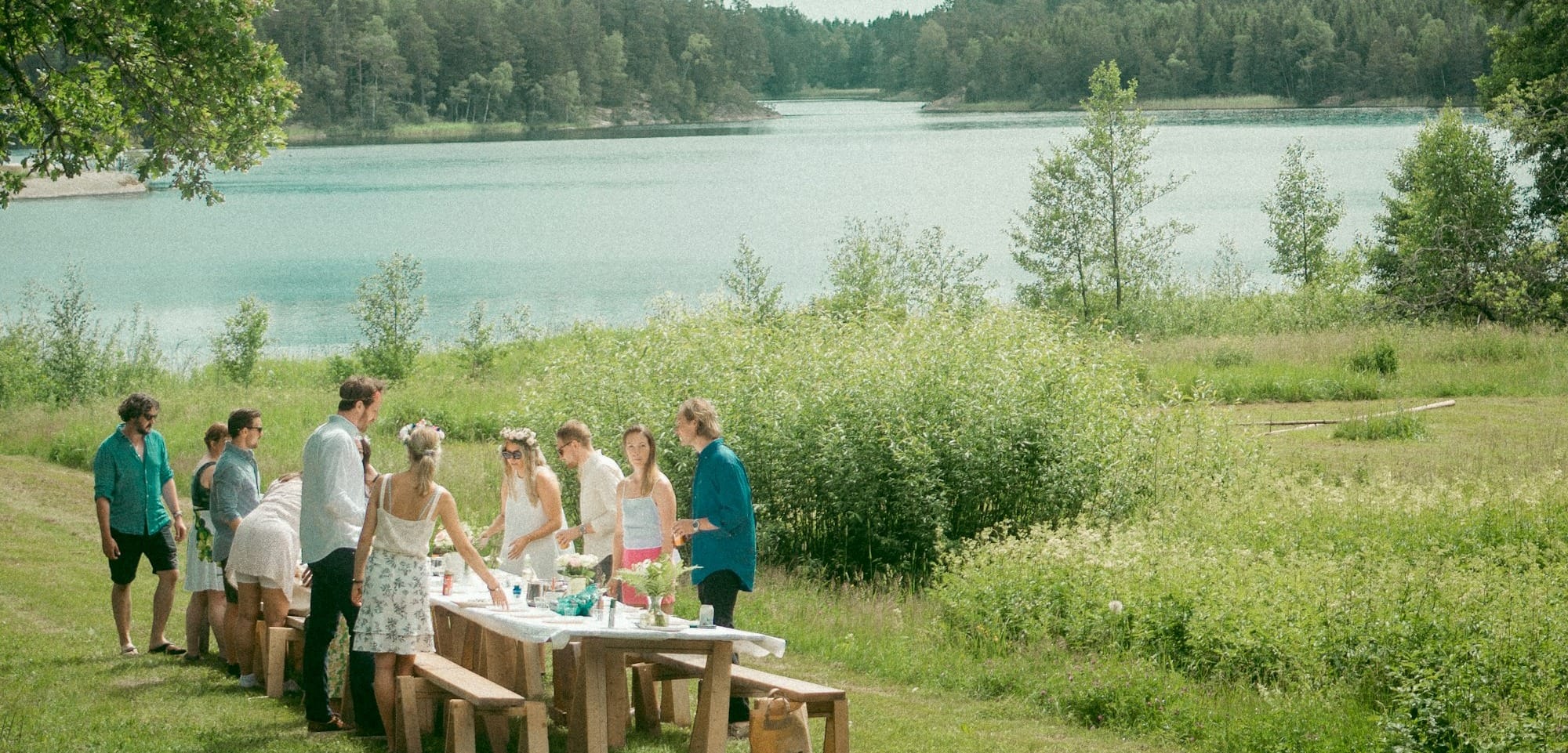 people sitting on brown wooden bench near lake during daytime